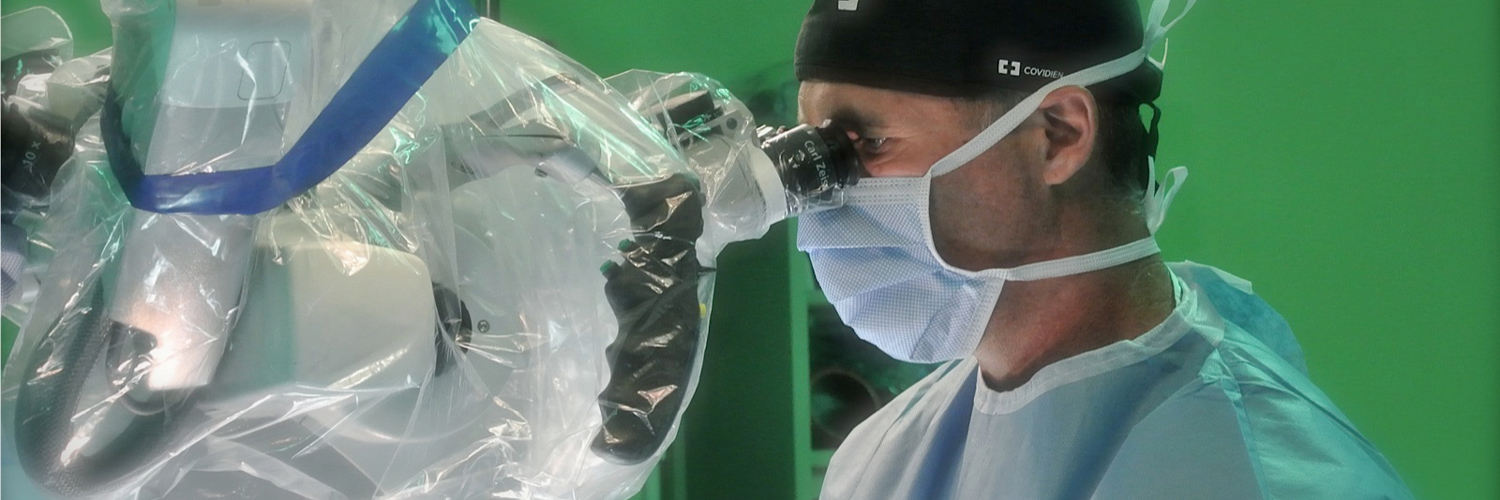 Dr. Patrick Roth peers through magnification during neurosurgical procedure